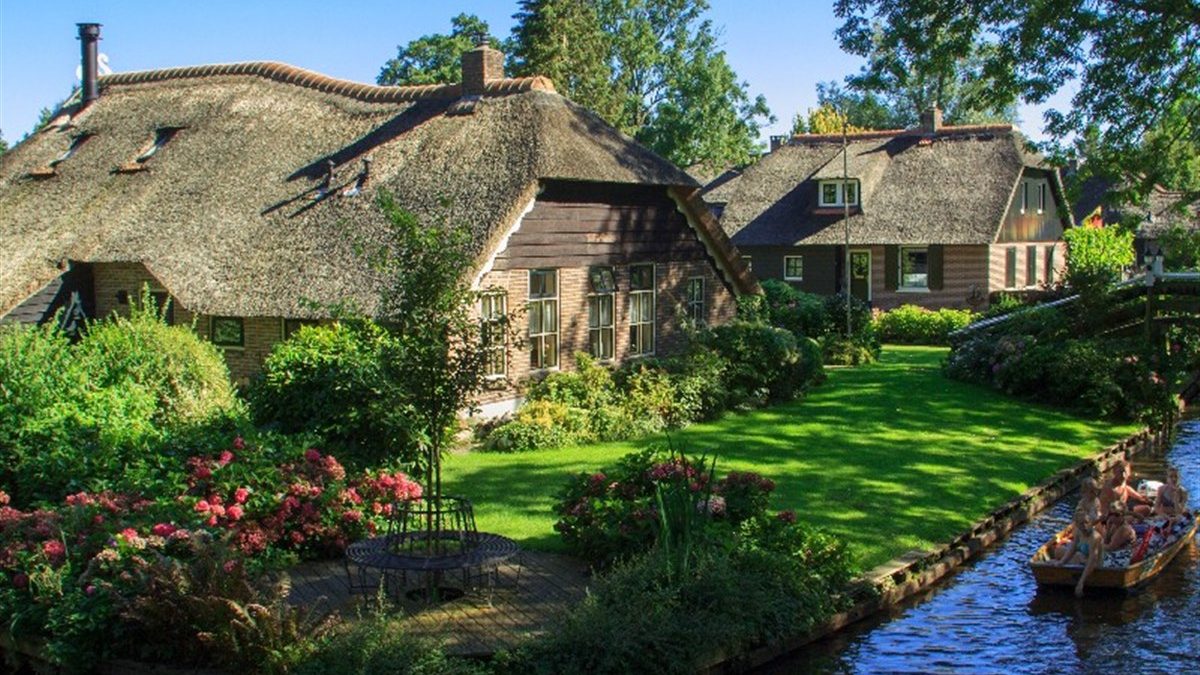 Reetgedeckte Bauernhäuser mit blühendem Garten an einer Gracht in Giethoorn
