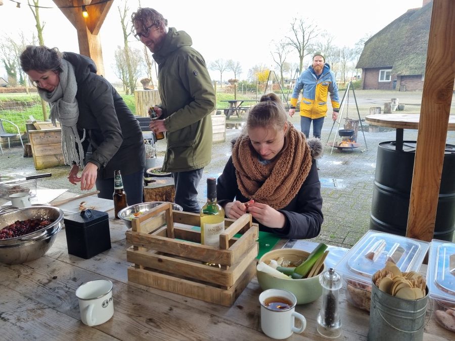 Teilnehmer schneiden Gemüse an einem Holztisch beim Kochworkshop