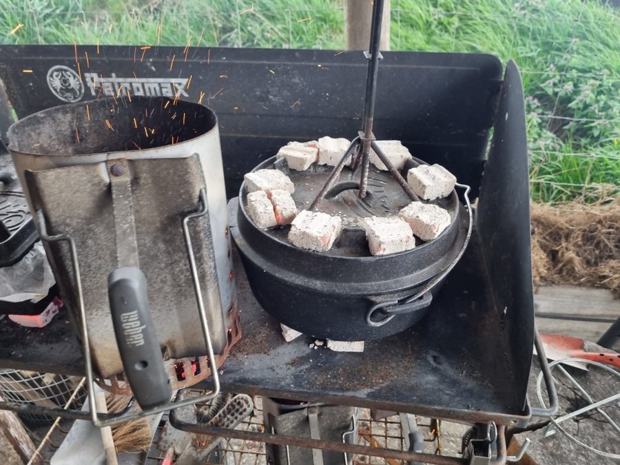 Dutch Oven mit Kohlen auf dem Deckel auf einem Außenherd