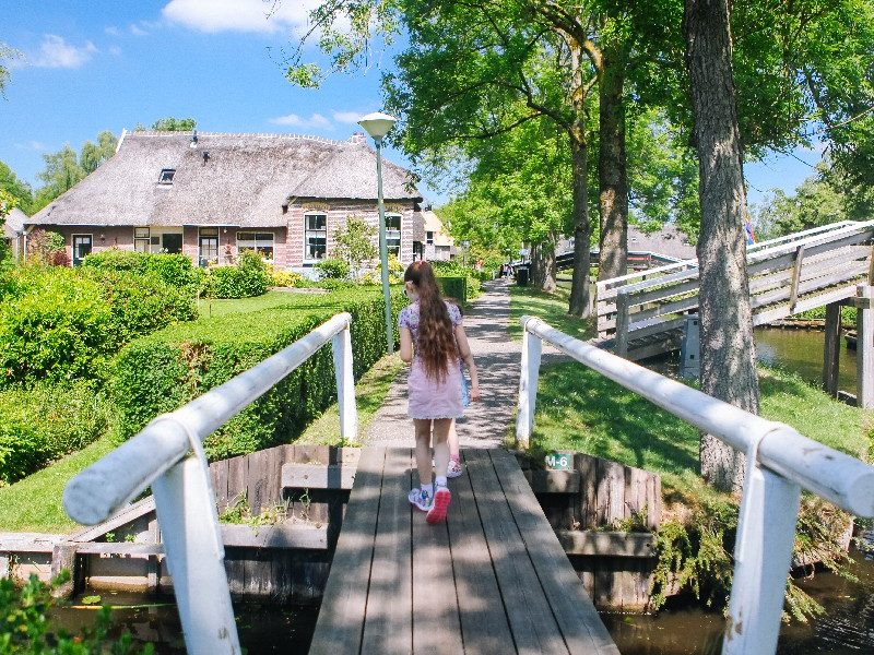 Girl walking over a white wooden bridge in Giethoorn