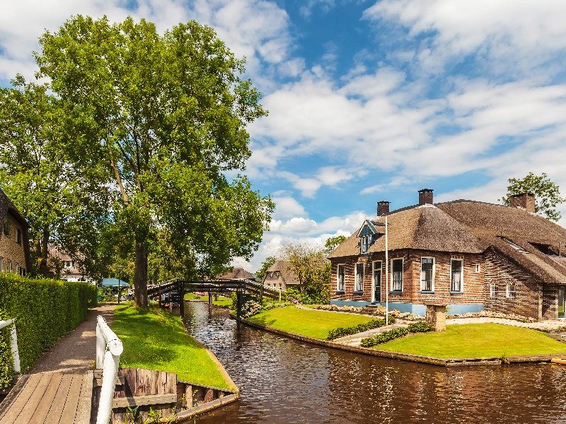 Quiet footpath alongside a canal with a thatched farmhouse in Giethoorn