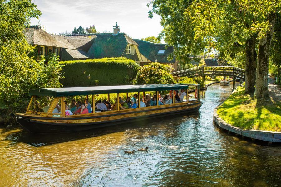 Canal cruise boat with visitors in a canal in Giethoorn
