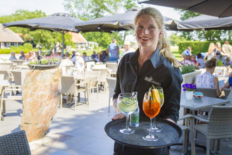 Kellnerin mit Getränken auf einer sonnigen Terrasse in Giethoorn
