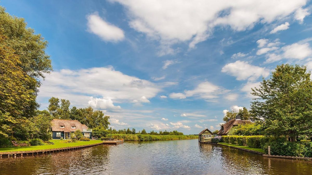 Breites Gewässer mit Schilfufern und Bauernhöfen in der Umgebung von Giethoorn
