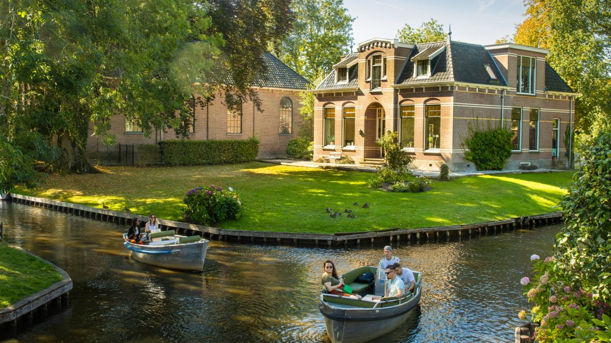 Huurbootjes op een gracht voor een statige villa in Giethoorn