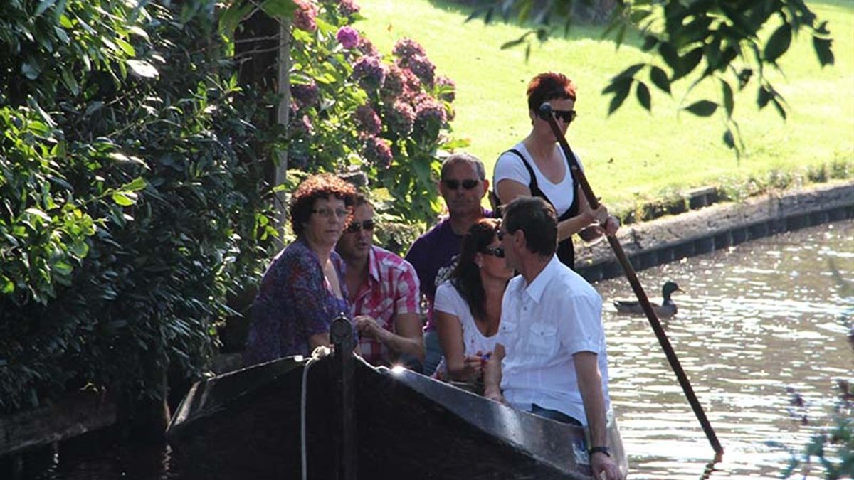 Group of visitors in a punter (traditional wooden boat) being poled through Giethoorn