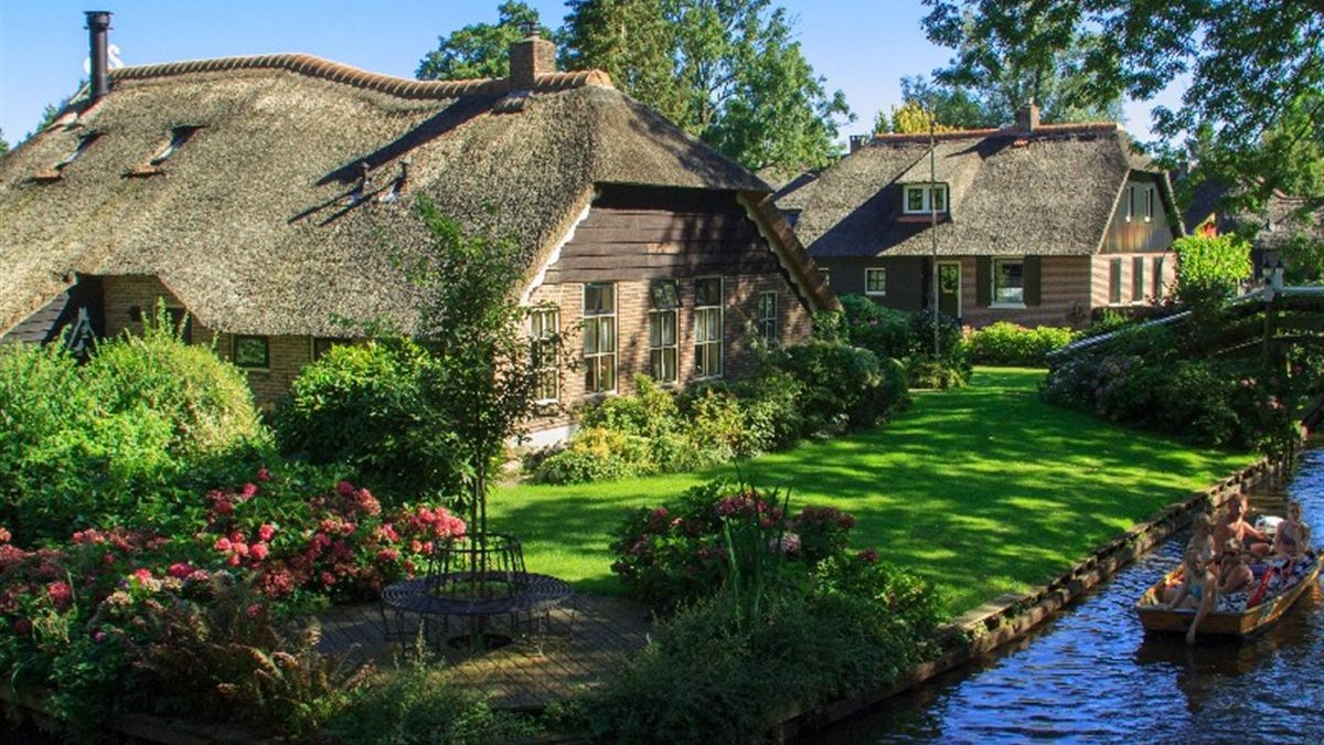 Thatched farmhouses with a flowering garden by the water in Giethoorn