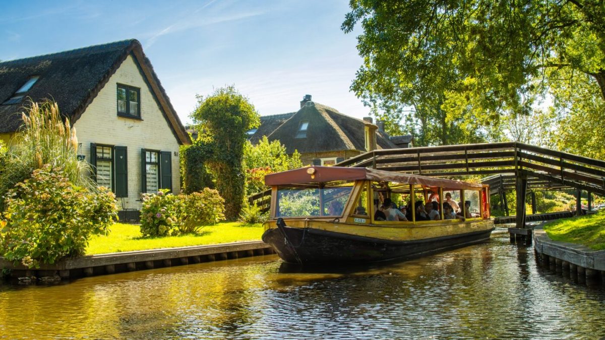 Tour boat with passengers sailing along a canal in Giethoorn