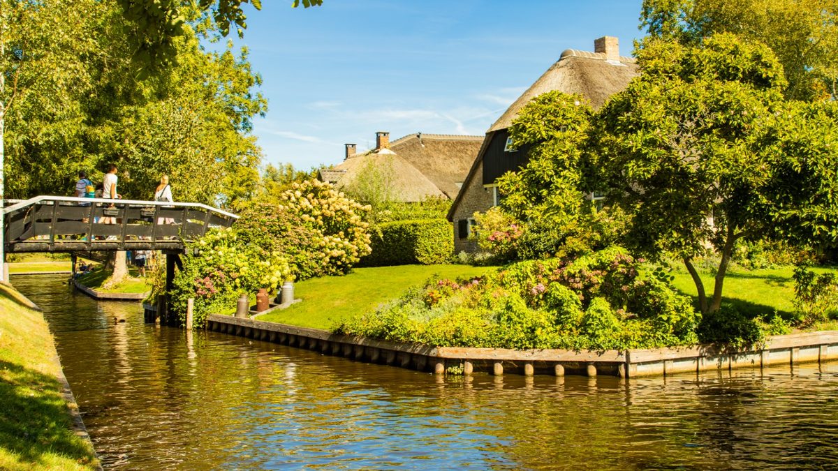 Gracht met houten bruggetje en rietgedekte boerderij in Giethoorn