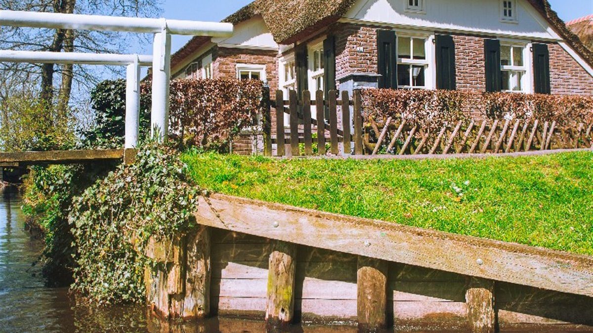 Thatched house with a white bridge by the water in Giethoorn
