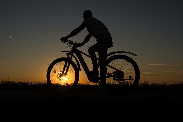 Silhouette eines Radfahrers auf einem E-Bike bei Sonnenuntergang
