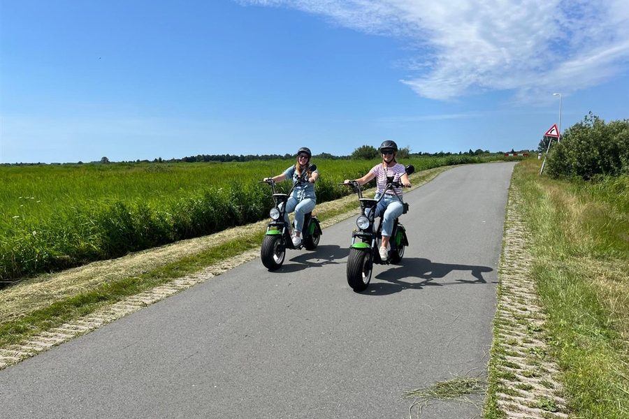 Zwei Besucher auf E-Choppern auf einer Straße durch den Polder bei Giethoorn