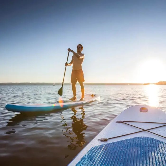 Stand-up paddleboarding on the water at sunset