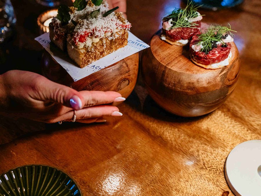 Small bites on wooden dishes being served at the table at ’t Achterhuus