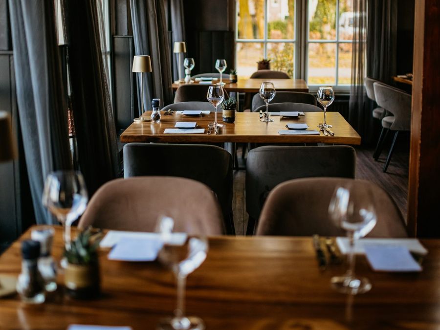Laid tables in the restaurant of ’t Achterhuus, with daylight through the windows