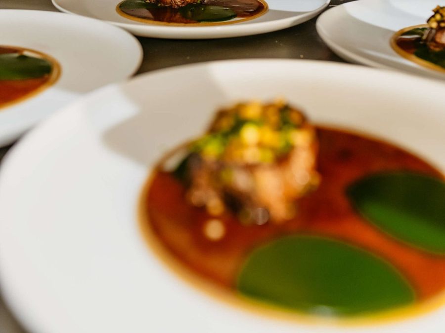 Plates with a plated dish at the pass in the kitchen of ’t Achterhuus