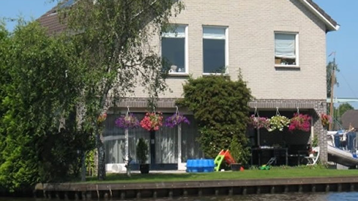 Appartement Hoek in Giethoorn, vom Wasser aus gesehen, mit Garten und Blumenkästen am Ufer