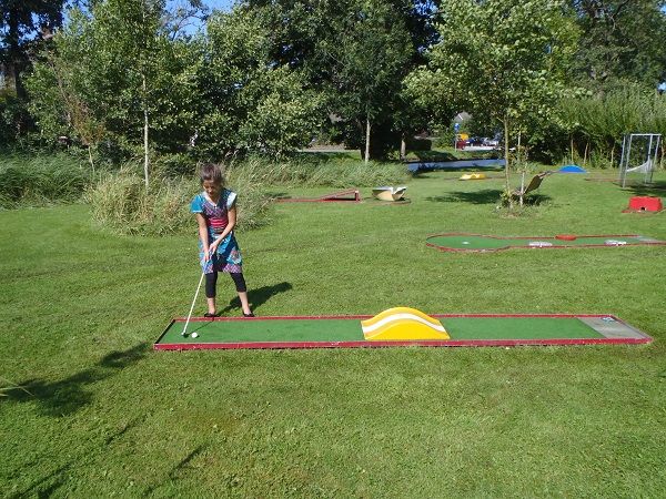 Kind spielt Minigolf auf einer Bahn im Gras bei Arendshorst