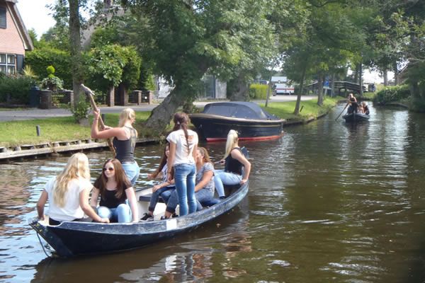 Gruppe junger Leute in einem traditionellen Punter auf einer Gracht in Giethoorn