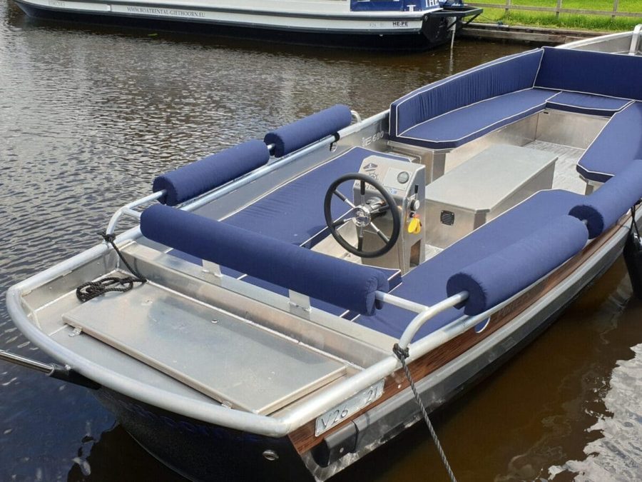 Elektrische Mietsloep mit Steuerrad und blauen Kissen von Boatrental Giethoorn am Steg