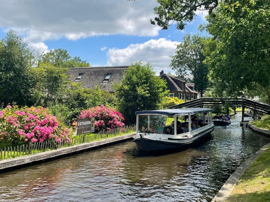Überdachtes Rundfahrtboot von Boatrental Giethoorn auf einer Gracht mit blühenden Hortensien