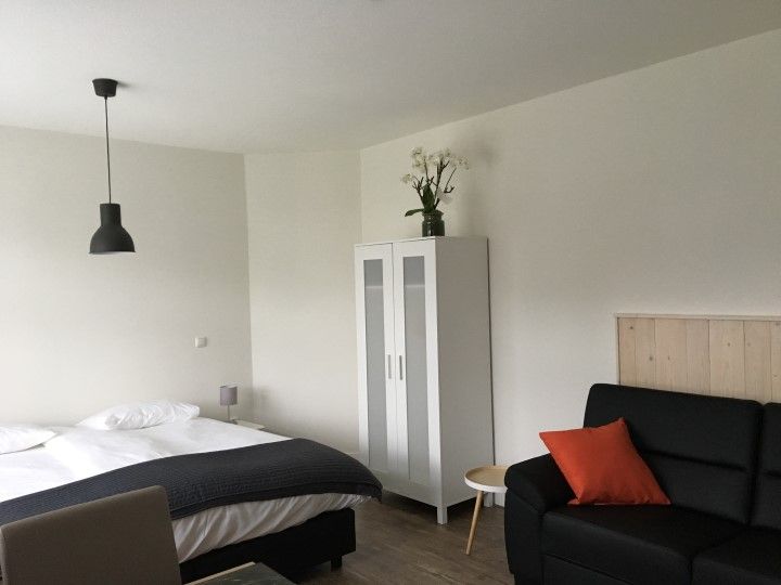 Bright bedsit with a double bed and sofa in the farmhouse at Camping D'Hof