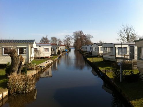 Static caravans beside a ditch with moorings at Camping D'Hof