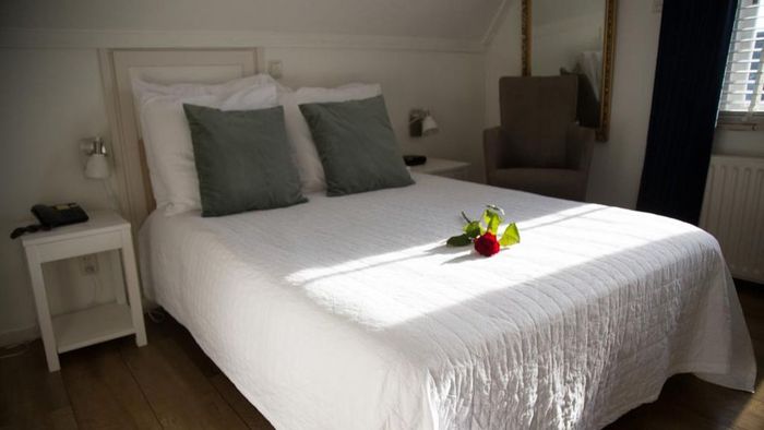 Basic room at De Dames van de Jonge with a white-made bed and bedside table