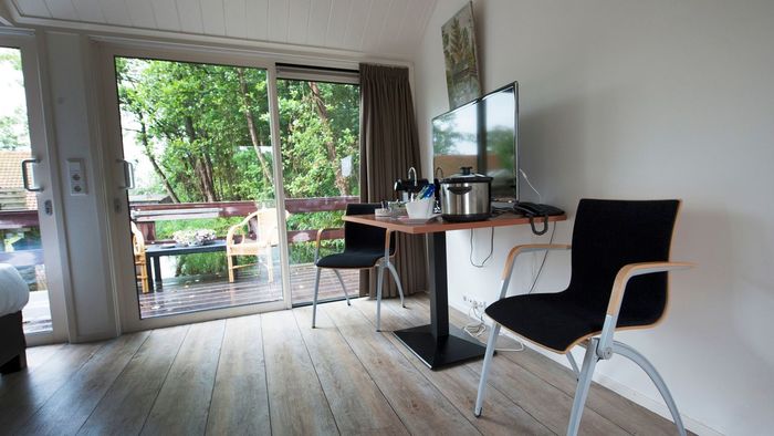 Comfort room at De Dames van de Jonge with table, chairs and glass sliding doors to the outside