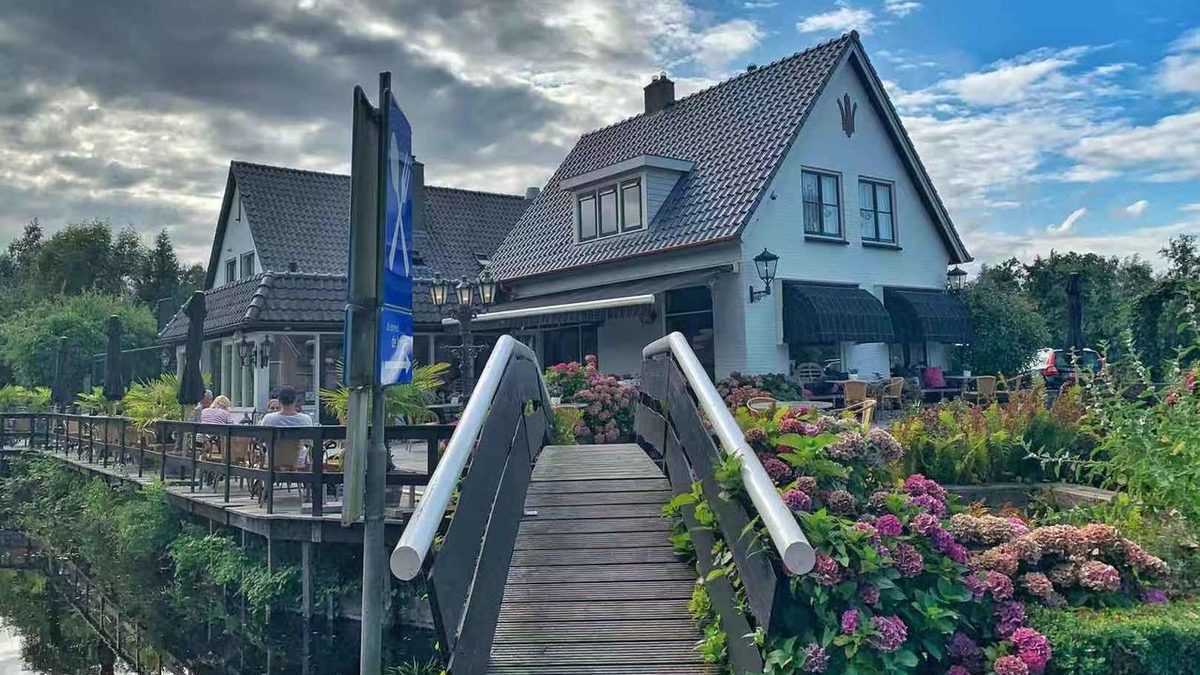 Hotel De Dames van de Jonge in Giethoorn with a small bridge and flowering garden by the water