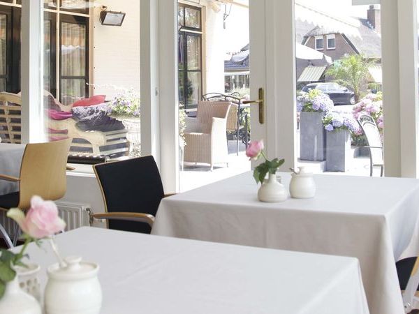Garden room of De Dames van de Jonge with laid tables and a view of the garden