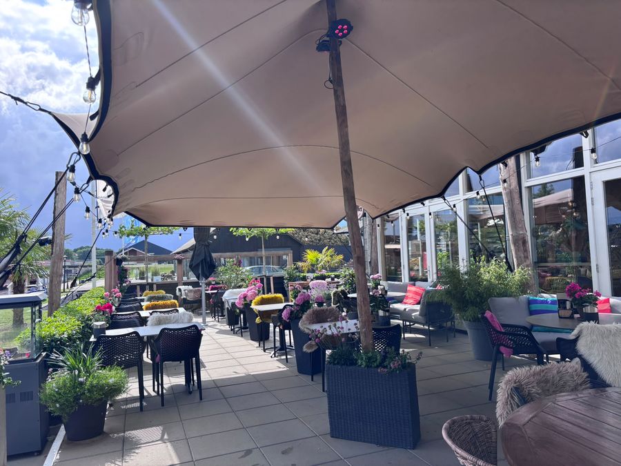 Terrasse von De Eetkamer van Giethoorn unter dem Spanndach, mit Tischen und Loungebänken