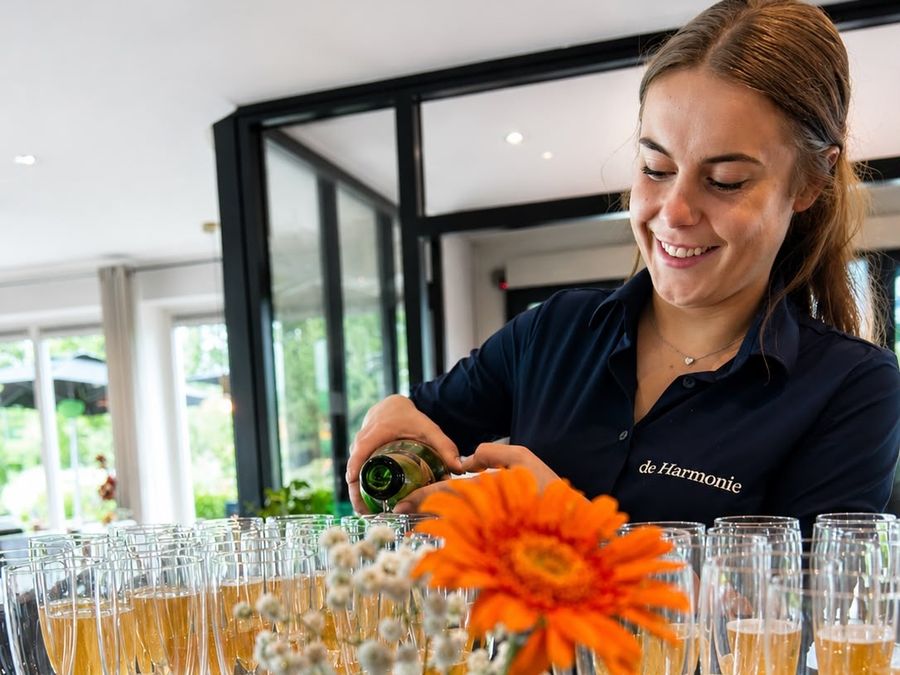 Member of staff at Hotel De Harmonie pouring glasses for a party