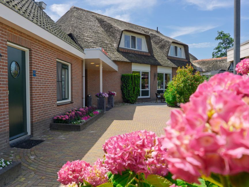 Front of Hotel De Harmonie with brick walls, thatched roofs and pink hydrangeas