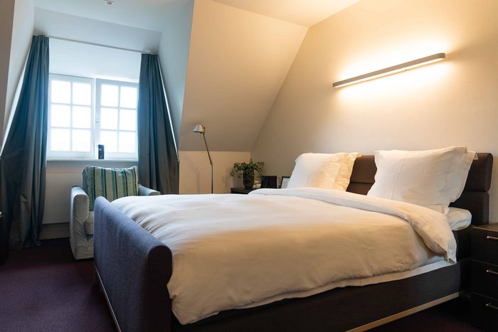 Junior suite of De Lindenhof with a double bed and a reading chair by the window
