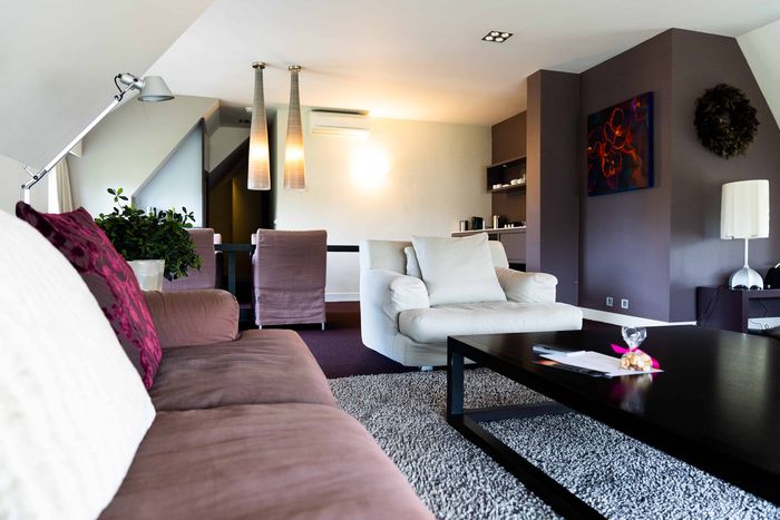 Senior suite of De Lindenhof with a seating area, sofa and coffee table under a sloping roof