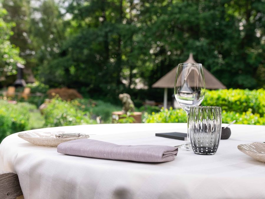 Laid table with a white tablecloth and glasses in the garden of De Lindenhof