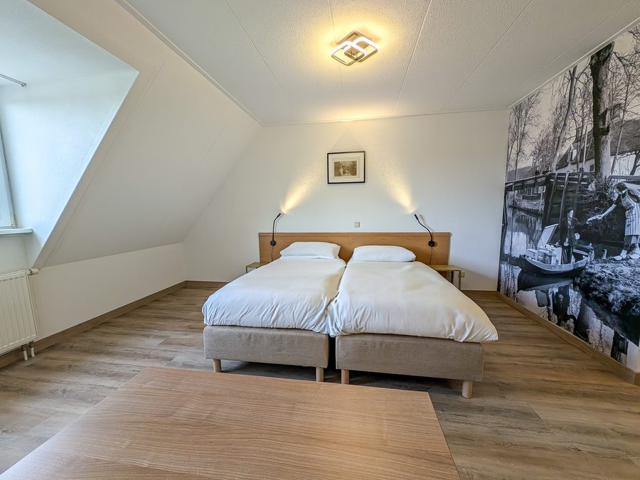 Hotel room at D'Olde Smidse with a linkable twin bed and a large black-and-white photo on the wall
