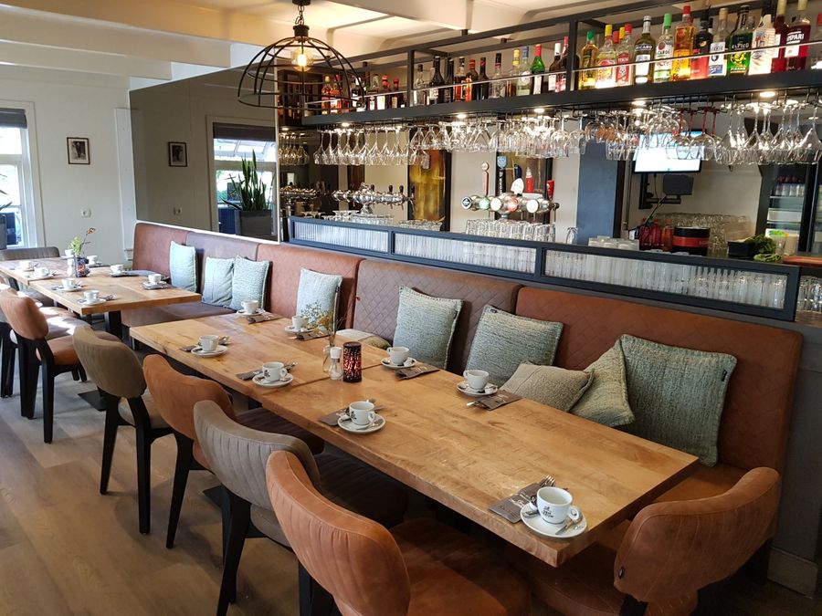 Restaurant of De Otterskooi with a long bench with cushions, wooden tables and the bar