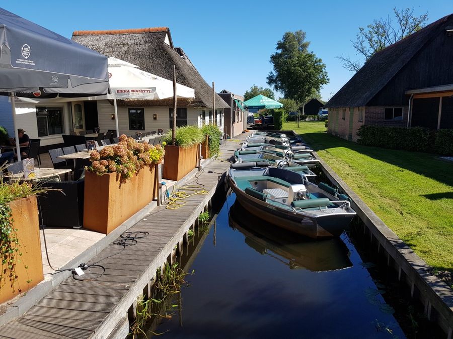 Rental boats in a narrow waterway next to the terrace of De Otterskooi