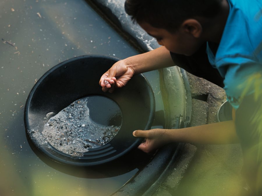 Kind sucht mit einer Goldwaschpfanne im Wasser bei De Oude Aarde nach Kristallen