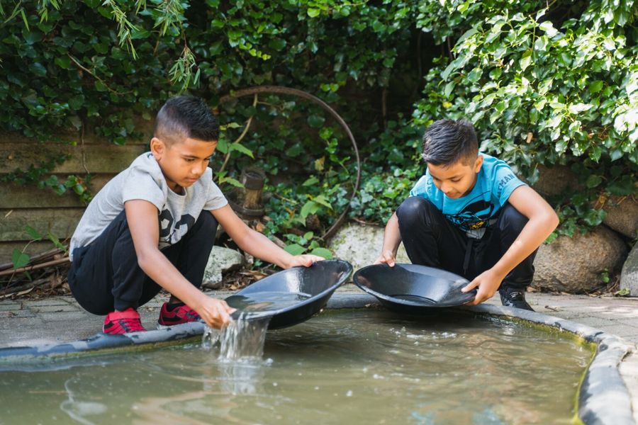 Zwei Kinder suchen mit einer Goldwaschpfanne im Teich bei De Oude Aarde nach Kristallen