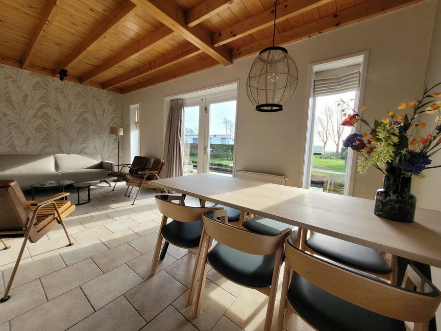 Wohnzimmer mit Esstisch und Flügeltüren in einem Ferienhaus von De Sloothaak