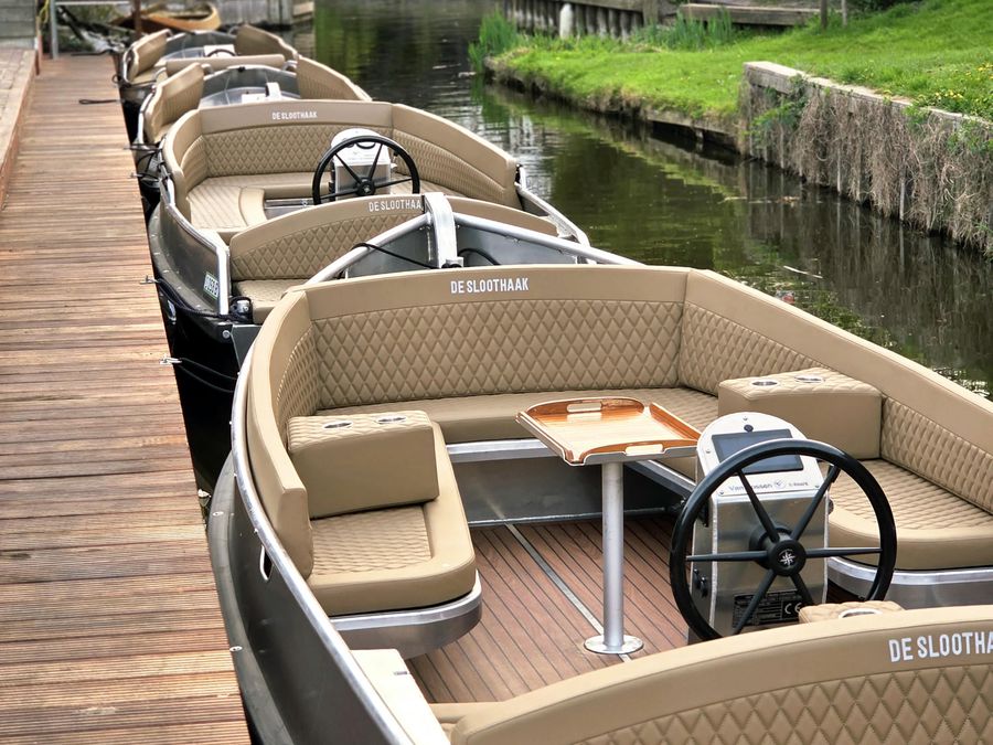 Luxe Lounge Sloep von De Sloothaak mit Tisch und Steuerrad am Steg