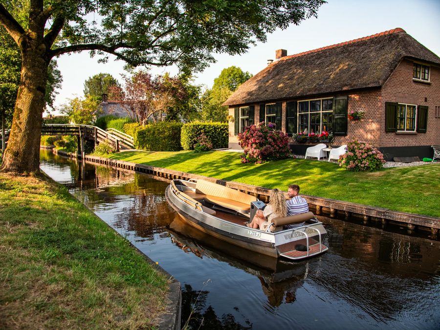 Mietsloep von De Sloothaak auf einer Gracht entlang eines Bauernhauses mit Reetdach