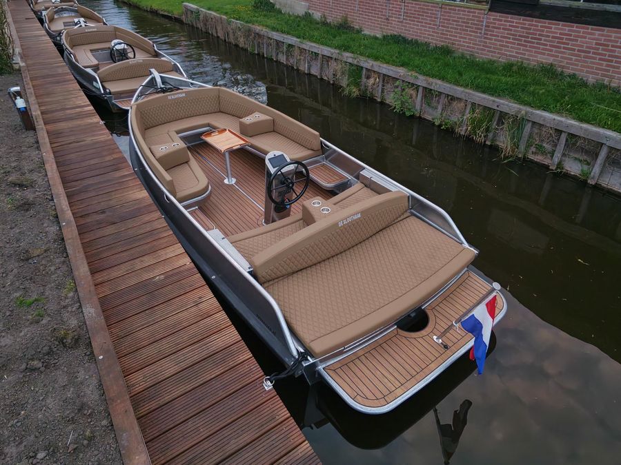 Große elektrische Loungesloep von De Sloothaak mit Kissen und Tisch am Steg