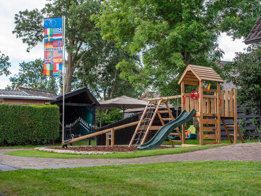 Spielgerät mit Rutsche auf der Wiese des Ferienparks De Sloothaak