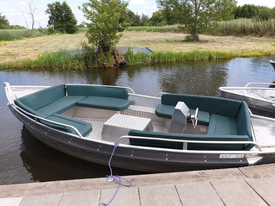 Elektrische Mietsloep mit grünen Kissen und Steuerrad am Steg von De Deukten