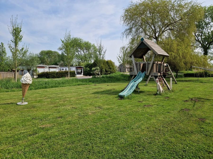Spielgerät mit Rutsche auf der Wiese neben der Terrasse von De Deukten