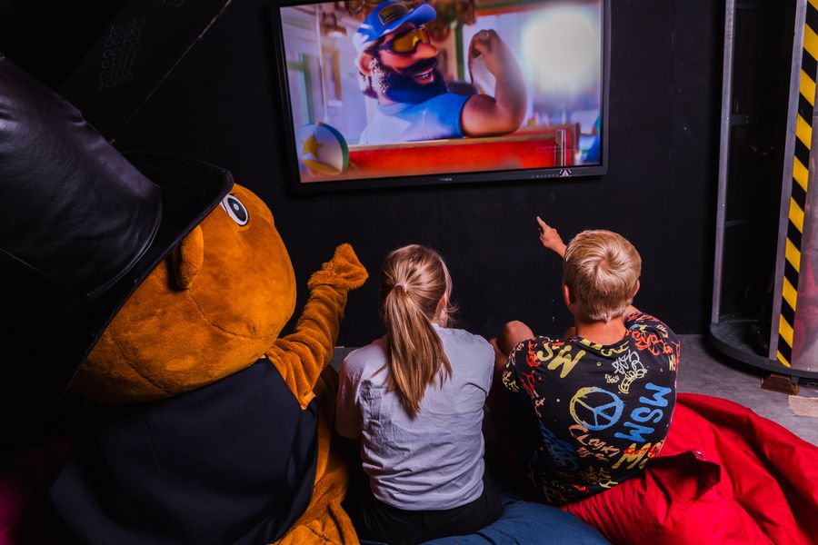 Kinder schauen gemeinsam mit einem Plüschbiber einen Zeichentrickfilm im Mini-Kino